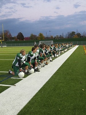 Last year's team kneeling on the sidelines during the opening ceremonies of the inaugural Team 55 Friday Night Lights game on October 18, 2013
