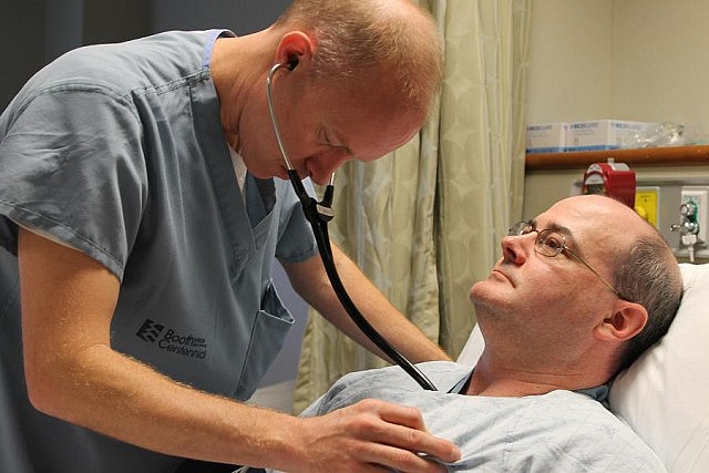 Interventional cardiologist Dr. Warren Ball listening to a patient's heart